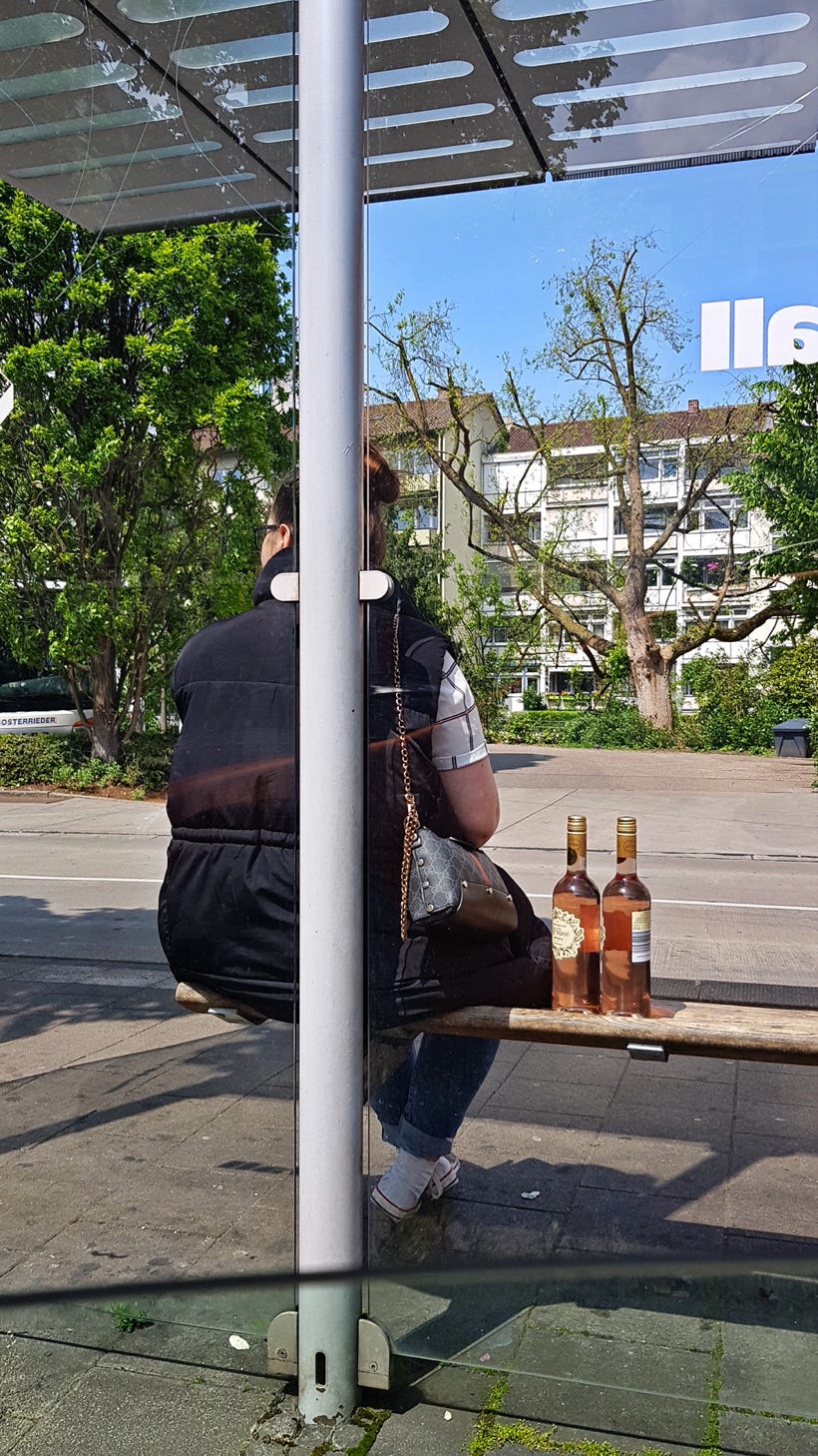 Woman waiting for the bus with two bottles of wine